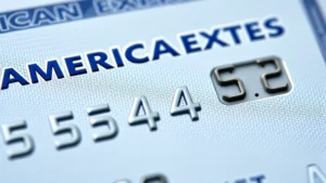 Close-up photograph of an American Express credit card front side showing the embossed account number and four-digit security code in the upper right corner, with shallow depth of field emphasizing the security code area